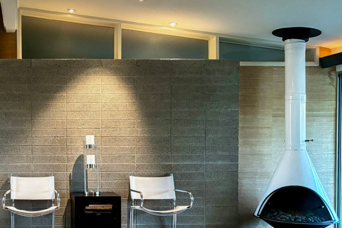Mid-century modern interior with a white Malm fireplace, clerestory windows, block wall, and chrome lounge chairs.