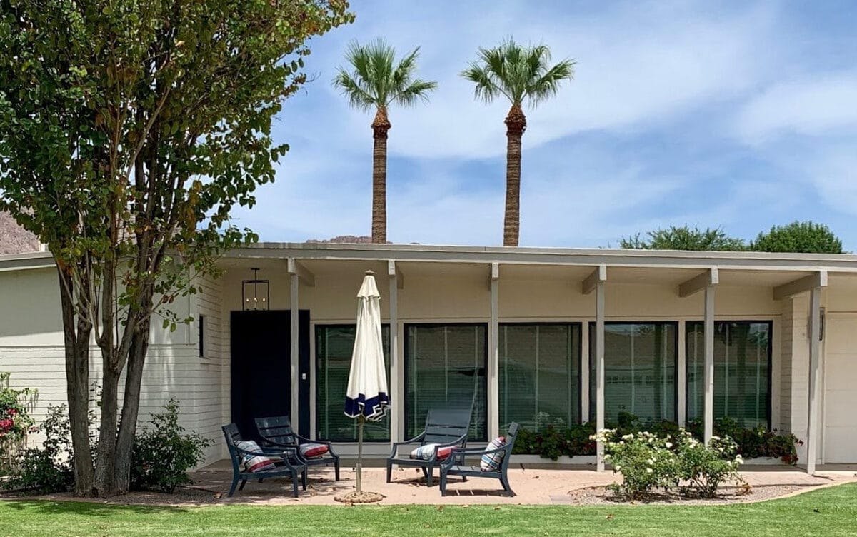 Schreiber mid-century modern home in Arcadia Phoenix with low roofline, shaded front patio, broad windows, palm trees, and lawn.