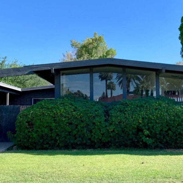 Ralph Haver mid-century modern home in Janet Manor Phoenix with black trim, brick facade, low roofline, clerestory windows, and front lawn.
