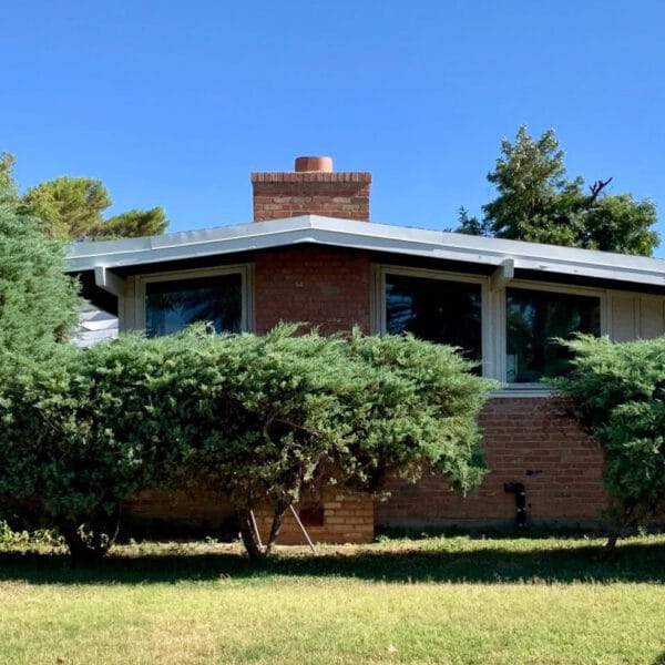 Ralph Haver mid-century modern home in Janet Manor Phoenix with brick chimney, low roofline, clerestory windows, mature landscaping, and front lawn.