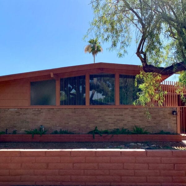 Ralph Haver mid-century modern home in Janet Manor Phoenix with orange block wall, low roofline, clerestory windows, gated entry, and mature trees.