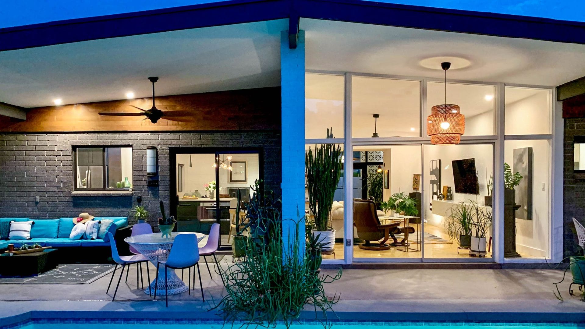 Phoenix mid-century modern home with a pool, glass walls, and covered patio at twilight.