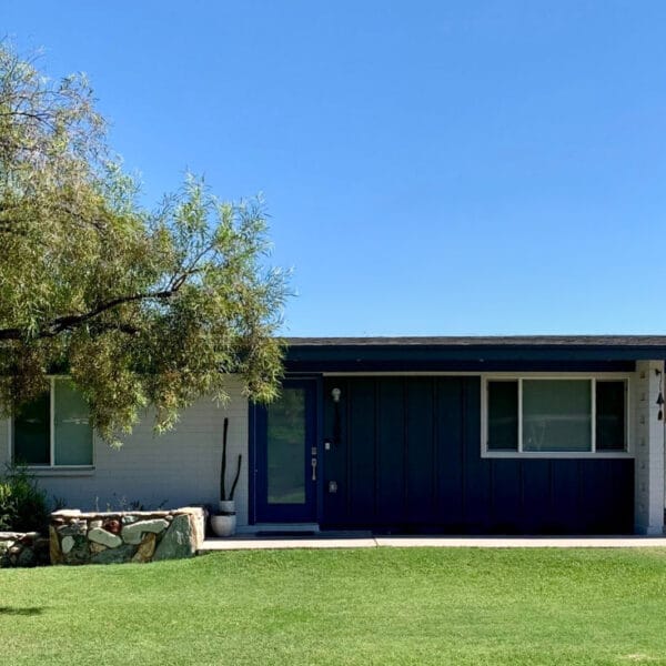 Ralph Haver mid-century modern home in Starlite Vista Phoenix with blue entry, low roofline, integrated carport, front lawn, and mature landscaping.