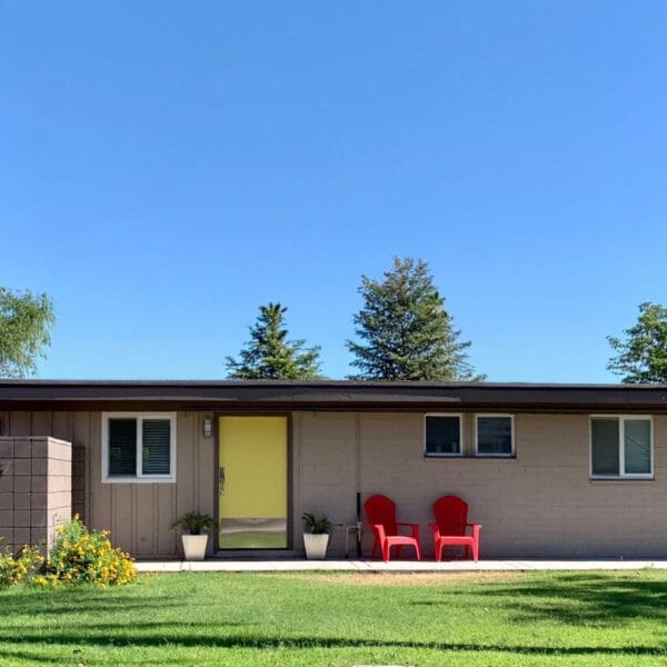 Ralph Haver mid-century modern home in Starlite Vista Phoenix with yellow front door, low roofline, block wall, front lawn, and carport.