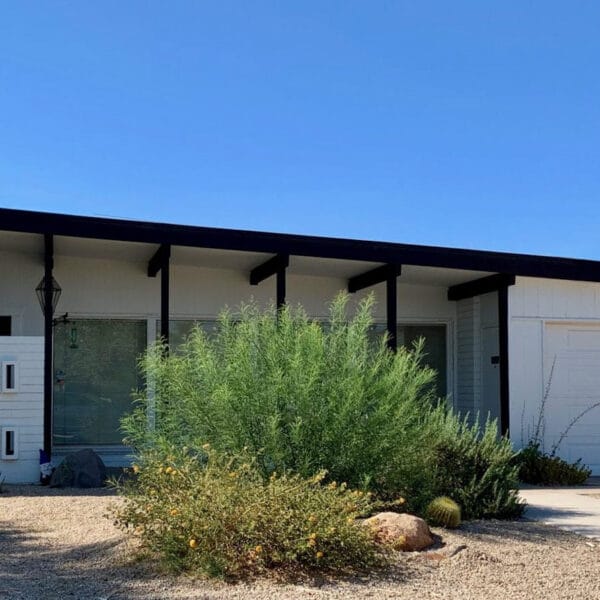 Charles and Arthur Schreiber mid-century modern home in Village Grove South Scottsdale with black beams, low roofline, decorative block details, garage, and desert landscaping.