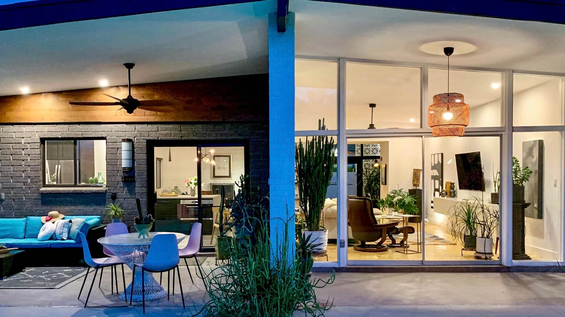 Phoenix mid-century modern home with a pool, glass walls, and covered patio at twilight.